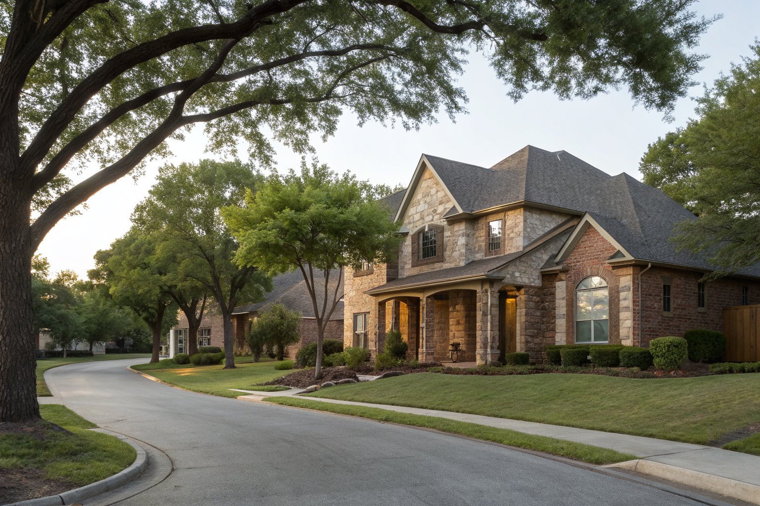Two-story brick and stone home with a front porch on a curving street