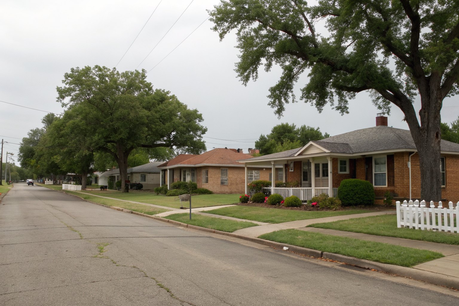 Small-town street of 1950s brick homes under pecan trees